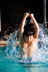 Boy splashing water in swimming pool