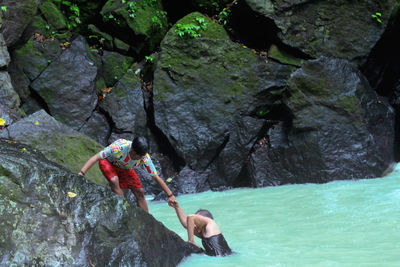 Rear view of people on rock at shore