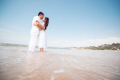 Couple kissing in sea against sky