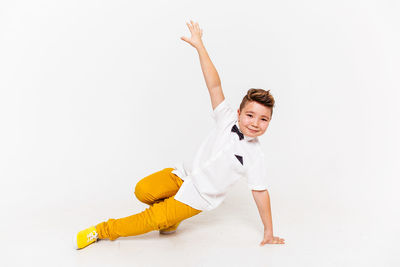 Happy boy with arms raised against white background