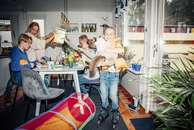 Portrait of smiling boy with cat while family eating breakfast at table