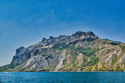 Scenic view of sea and mountains against blue sky