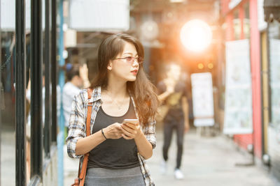 Woman looking away while standing footpath