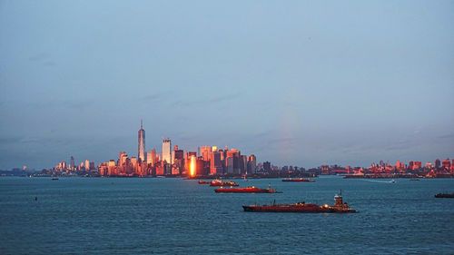 Sea by illuminated city against sky