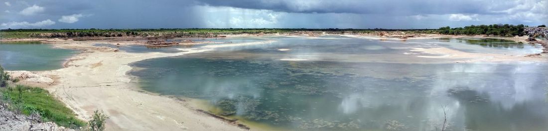 Panoramic view of people on landscape against cloudy sky