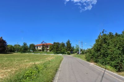 Road amidst trees against blue sky