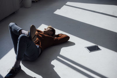 Businessman with hands behind head lying on floor in office