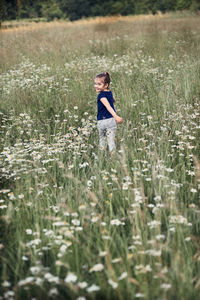 Portrait of smiling girl walking amidst plants on field