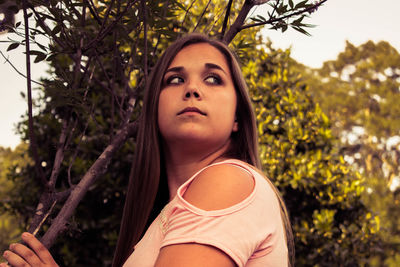 Close-up of young woman against trees