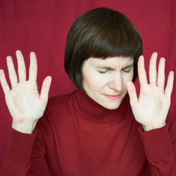 Portrait of mature woman in distress, hands up, stoping situation, stop gest. agitated tensed face