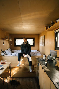 Side view of woman sitting on floor at home