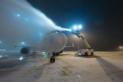 Deicing of airplane before flight. winter frosty night and ground service at airport.