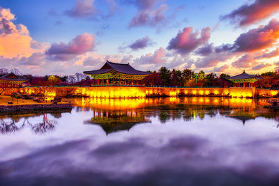 Reflection of illuminated building in lake at sunset