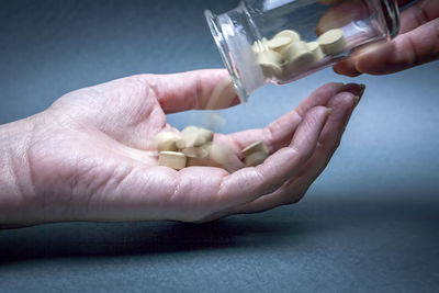 Close-up of hands holding glass over white background