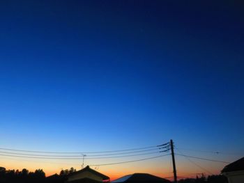 Silhouette electricity pylon against clear blue sky