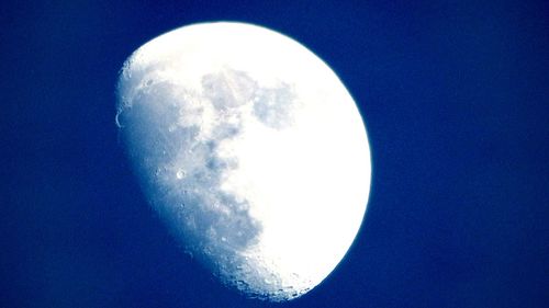 Low angle view of moon against clear blue sky