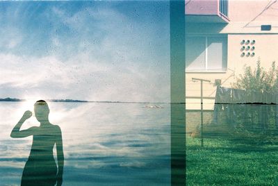 Rear view of woman standing by swimming pool against sky