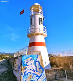 Lighthouse by sea against sky