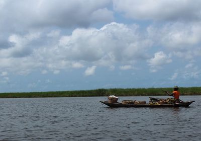 People in boat on river against sky