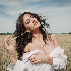 Portrait of young woman standing against sky