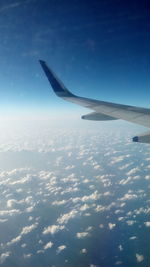 Aerial view of airplane wing over clouds