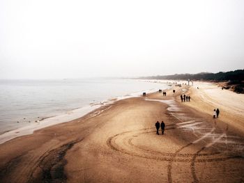 People on road by sea against clear sky