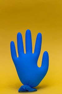 Close-up of human hand against yellow background