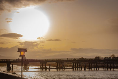 Pier over sea against sky during sunset