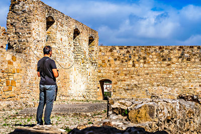 Man standing against old wall