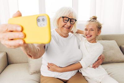 Portrait of young woman using mobile phone while sitting on sofa at home