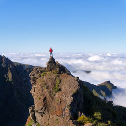 Man standing on rock looking at mountain against sky