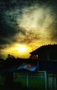 Houses against cloudy sky at sunset