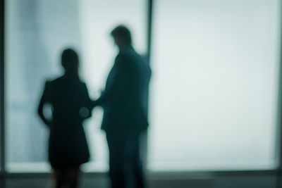 Defocused image of man and woman standing by window