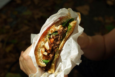 Vegan burger half eaten held in hand showing ingredients