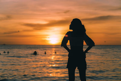 Silhouette woman standing at beach during sunset