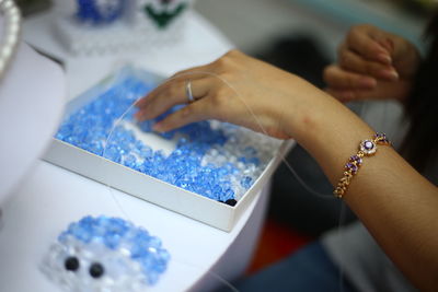 Cropped image of woman working on beads at table