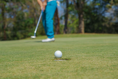 Low section of person holding ball on grass