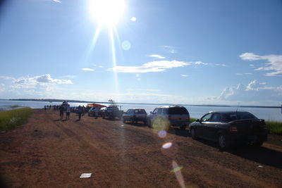 Cars on road by sea against sky