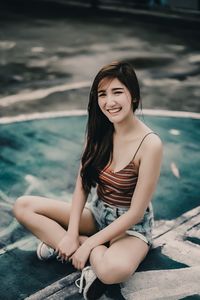 Beautiful young woman sitting at sea shore