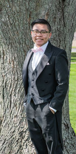 Portrait of man standing by tree trunk