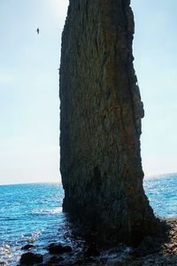 Rock formation on sea shore against sky