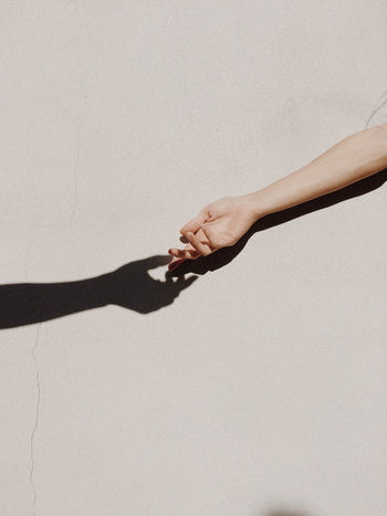 Cropped hands of people against gray wall