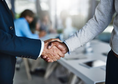 Midsection of business people shaking hands