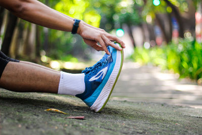 Low section of man tying shoelace