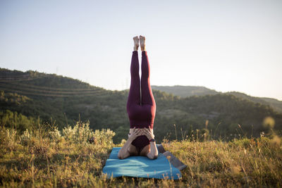 Midsection of woman with arms raised on field against clear sky