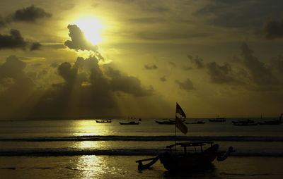 Silhouette boats in sea against sky during sunset