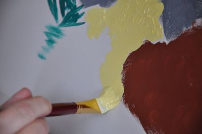 Close-up of hand holding yellow paint on table