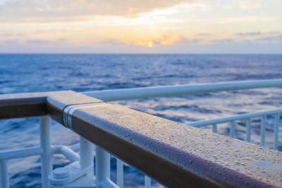 Close-up of railing against sea during sunset