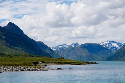 Scenic view of river and mountains against cloudy sky