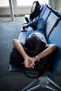 Woman lying down on chairs at airport